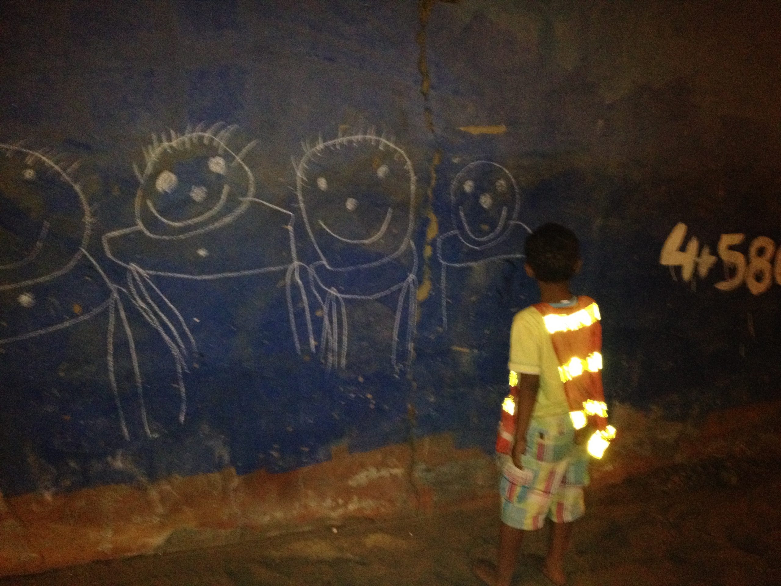 Boy drawing simple picture on the wall of three smiling people